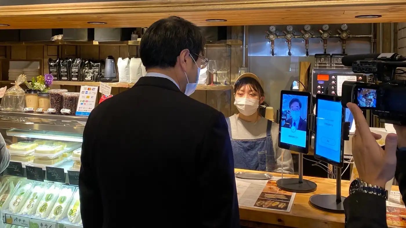 Японская компания Glory запустила тестирование системы бесконтактной оплаты, которая способна распознавать лица людей в защитных масках.